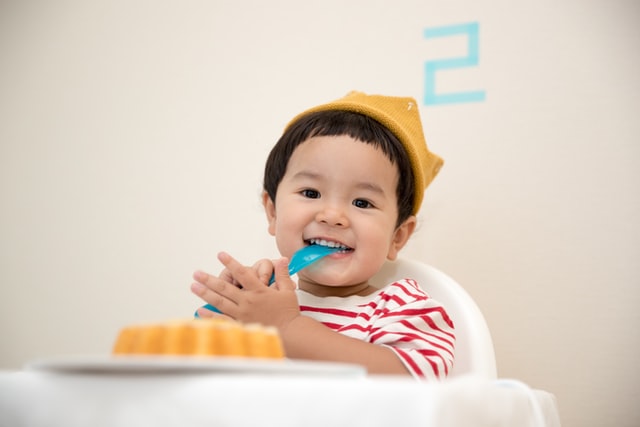 Bambino che mangia a una festa con la forchetta in bocca e che sorride