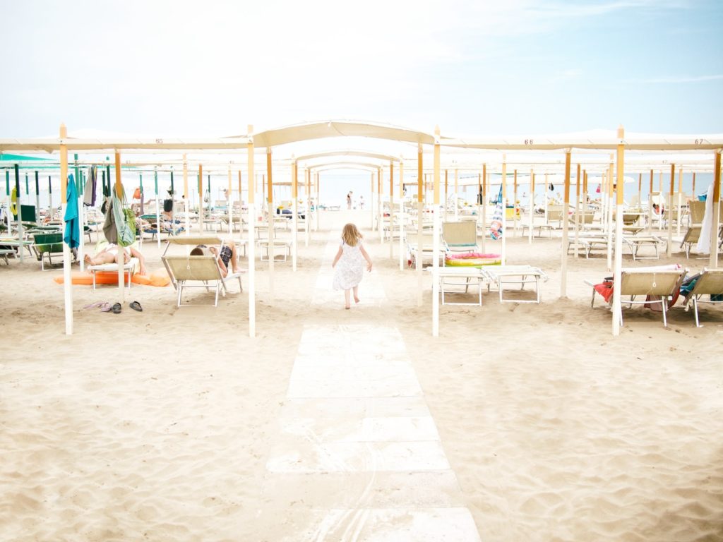 spiaggia con lettini e bambina che corre verso il mare.
festa per bambini in uno stabilimento balneare.