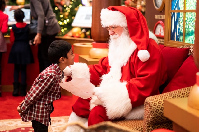 Bambino che sorride a uomo travestito da babbo natale