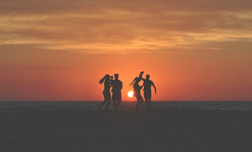 ragazzi che ballano al tramonto in spiaggia