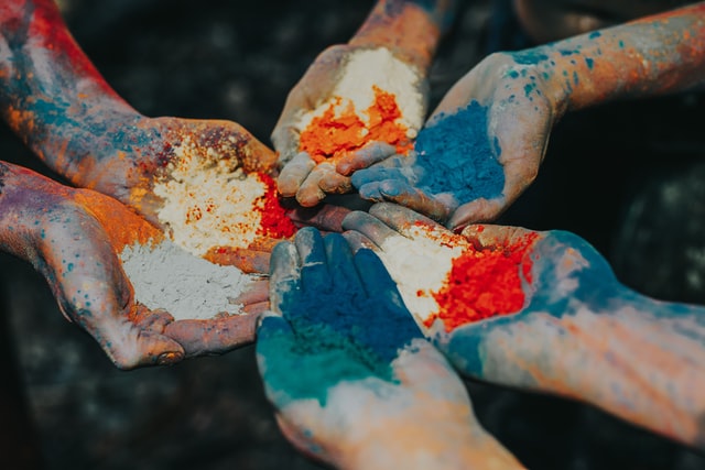 Sei mani in cerchio con sopra le classiche polveri Holi color